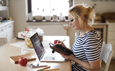 A woman writing down something in her daily planner so she doesn't forget.