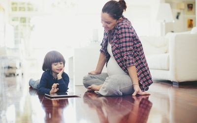 Child and parent sitting on the floor together looking at a tablet