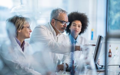 Three researchers in laboratory looking at computer screen